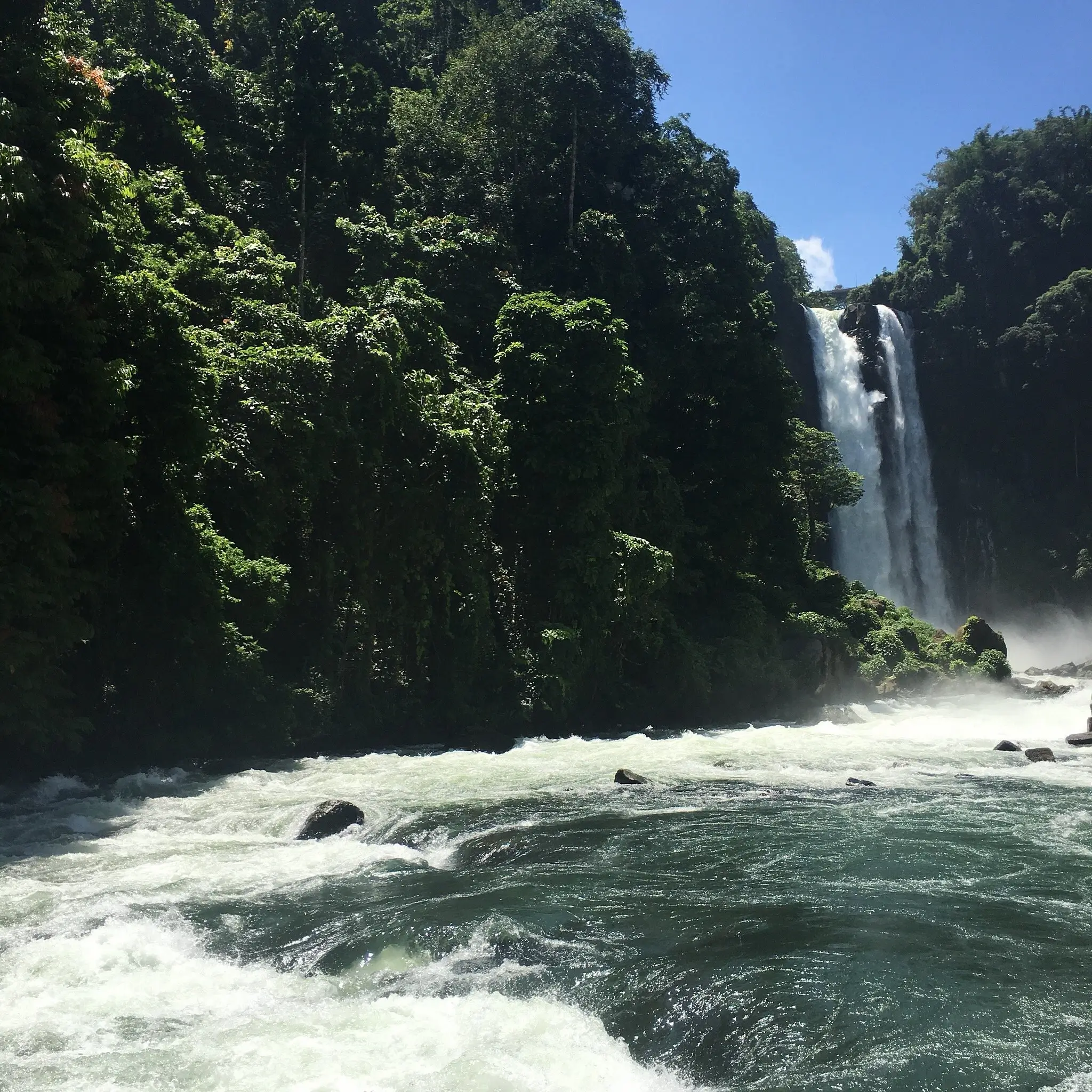 A photo shot close to the waters of Maria Cristina Falls, one of the most iconic tourist attractions in Mindanao. The white foam from the water can be seen, leading the eye to the twin showers framed by grassy rock formations.