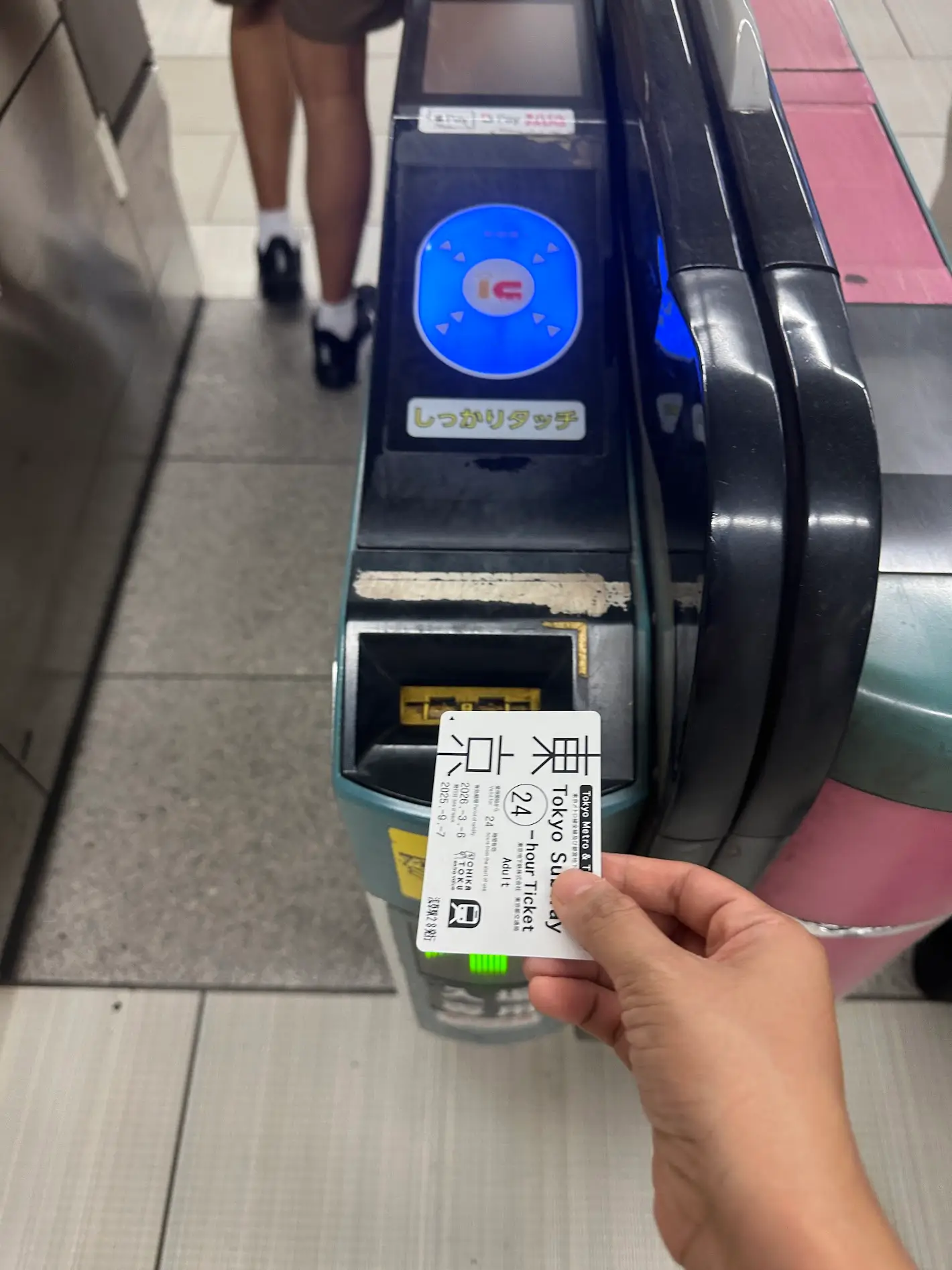 A hand holding a Tokyo subway 24 hour ticket while entering a station gate with a glowing blue IC reader. Simple Japanese Phrases for Travellers