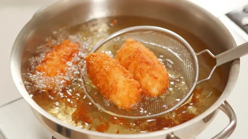 Best street food in Tokyo shown through golden croquettes frying in hot oil at a street food stall