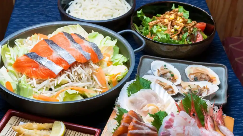 Assortment of fresh Hokkaido seafood including salmon, sashimi, clams, and udon—showcasing Japan’s northern regional cuisine.