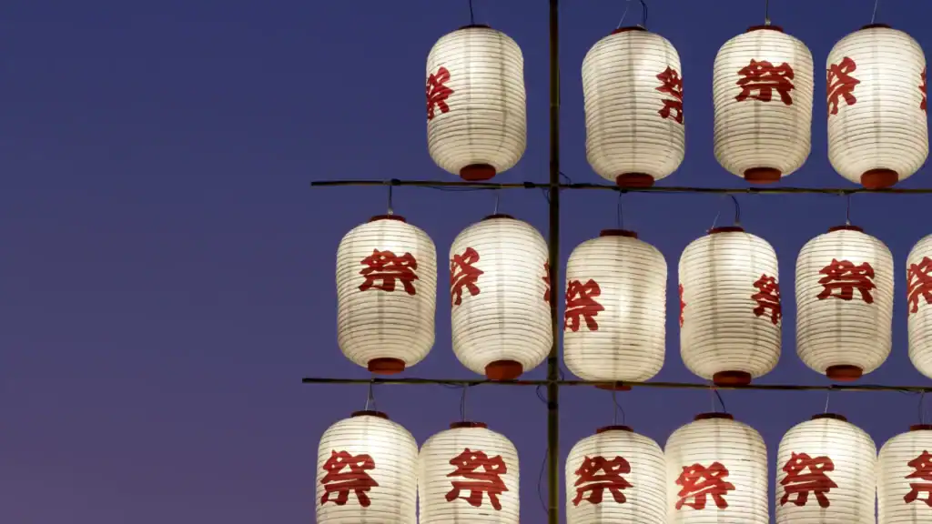 Paper lanterns hanging at dusk during traditional festivals in Japan, symbolizing community celebration and seasonal matsuri traditions.