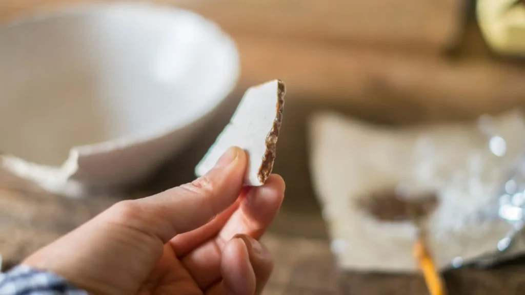 Things to Do in Osaka learning kintsugi pottery repair by holding a broken ceramic piece during a hands on workshop.