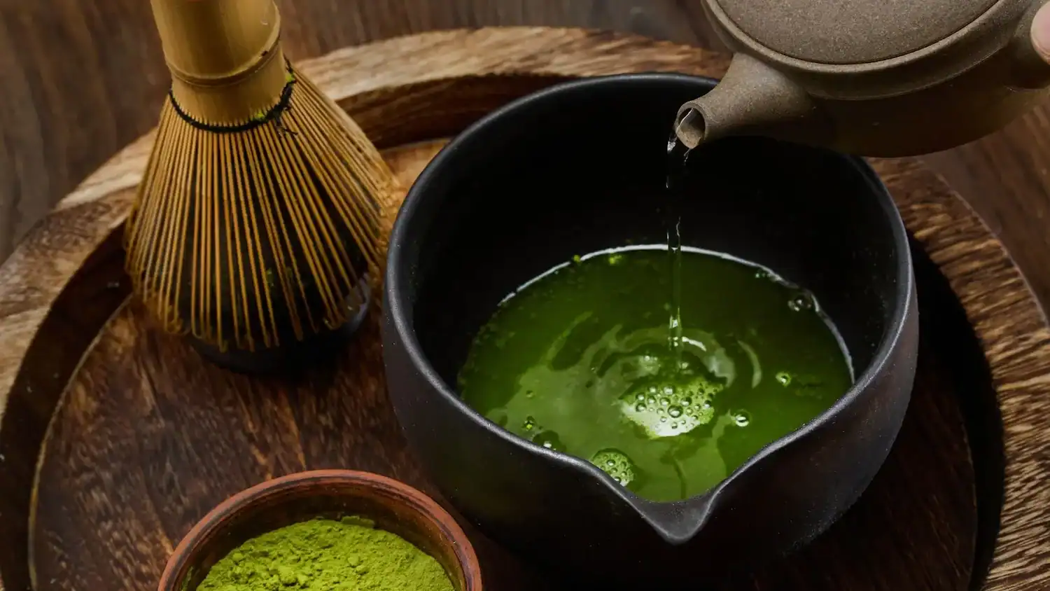 Japanese matcha tea being whisked and poured into a bowl during a traditional tea preparation—one of the essential Japanese drinks to try in Japan.