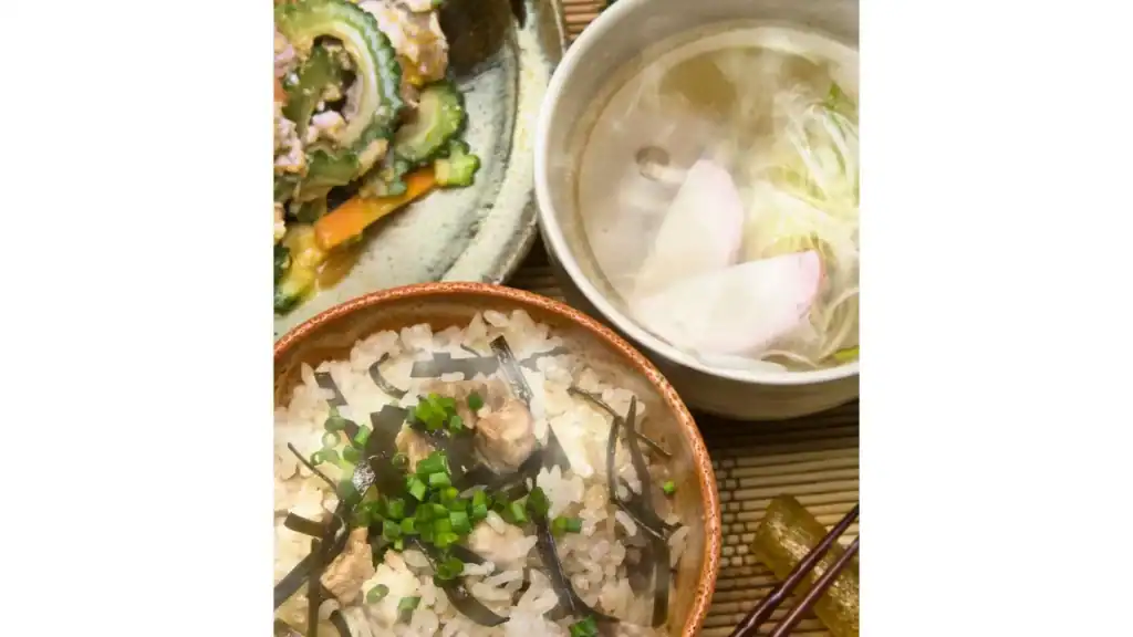 Traditional Okinawan dishes including rice with pork and kombu, bitter melon goya champuru, and soup—regional Japanese foods unique to Okinawa.