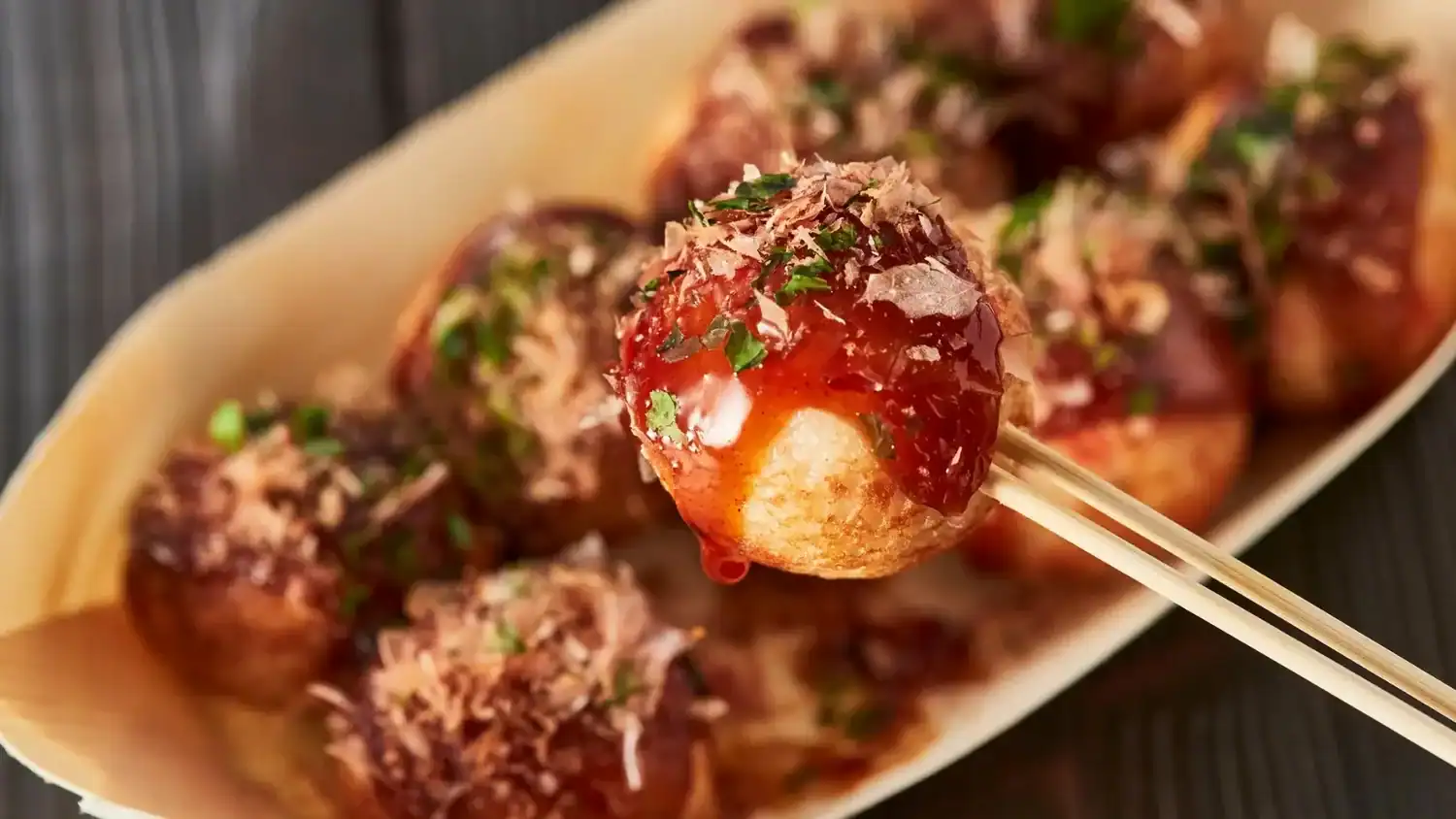 Takoyaki octopus balls topped with sauce, bonito flakes, and herbs, a famous Japanese street food from Osaka.”