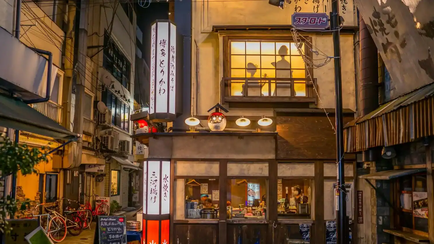 Narrow Tokyo alleyway with izakaya restaurants at night, social things to do in Tokyo