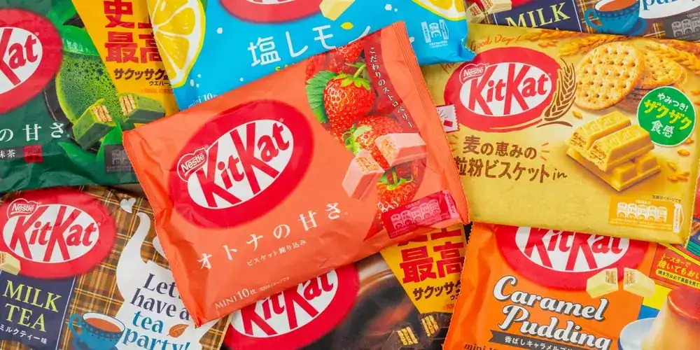 Assorted Japanese KitKat flavors including matcha, strawberry, caramel pudding, milk tea, and regional varieties displayed in colorful packaging. One of the few Japanese Foods to try in Japan