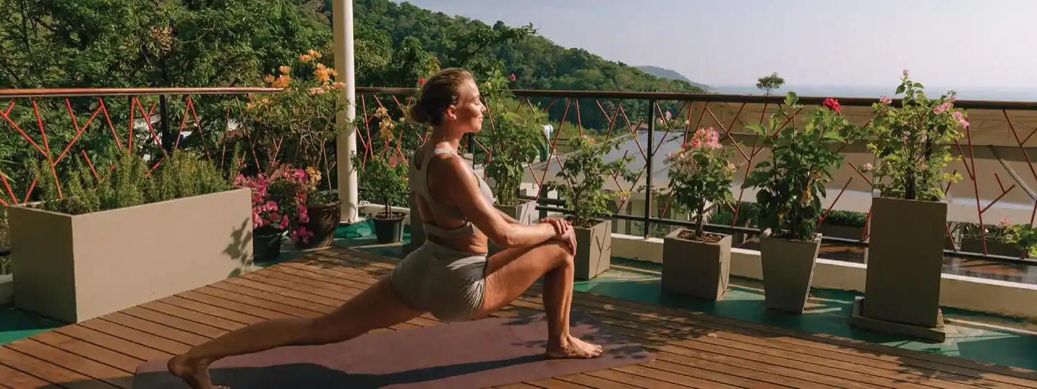 A woman doing lunges on the rooftop if CC's Hideaway, one of the most affordable yoga retreats in Phuket.