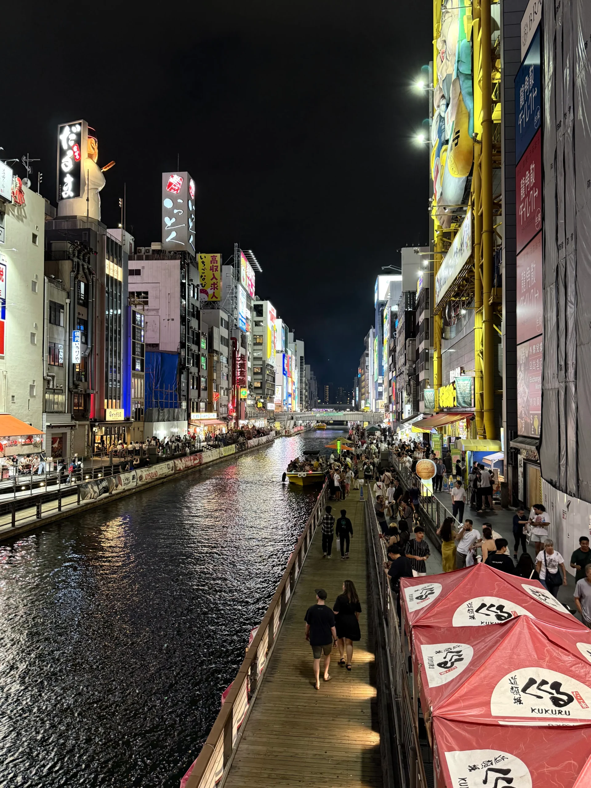 Things to Do in Osaka – night view of Dotonbori canal lined with neon-lit buildings and busy pedestrian walkways.