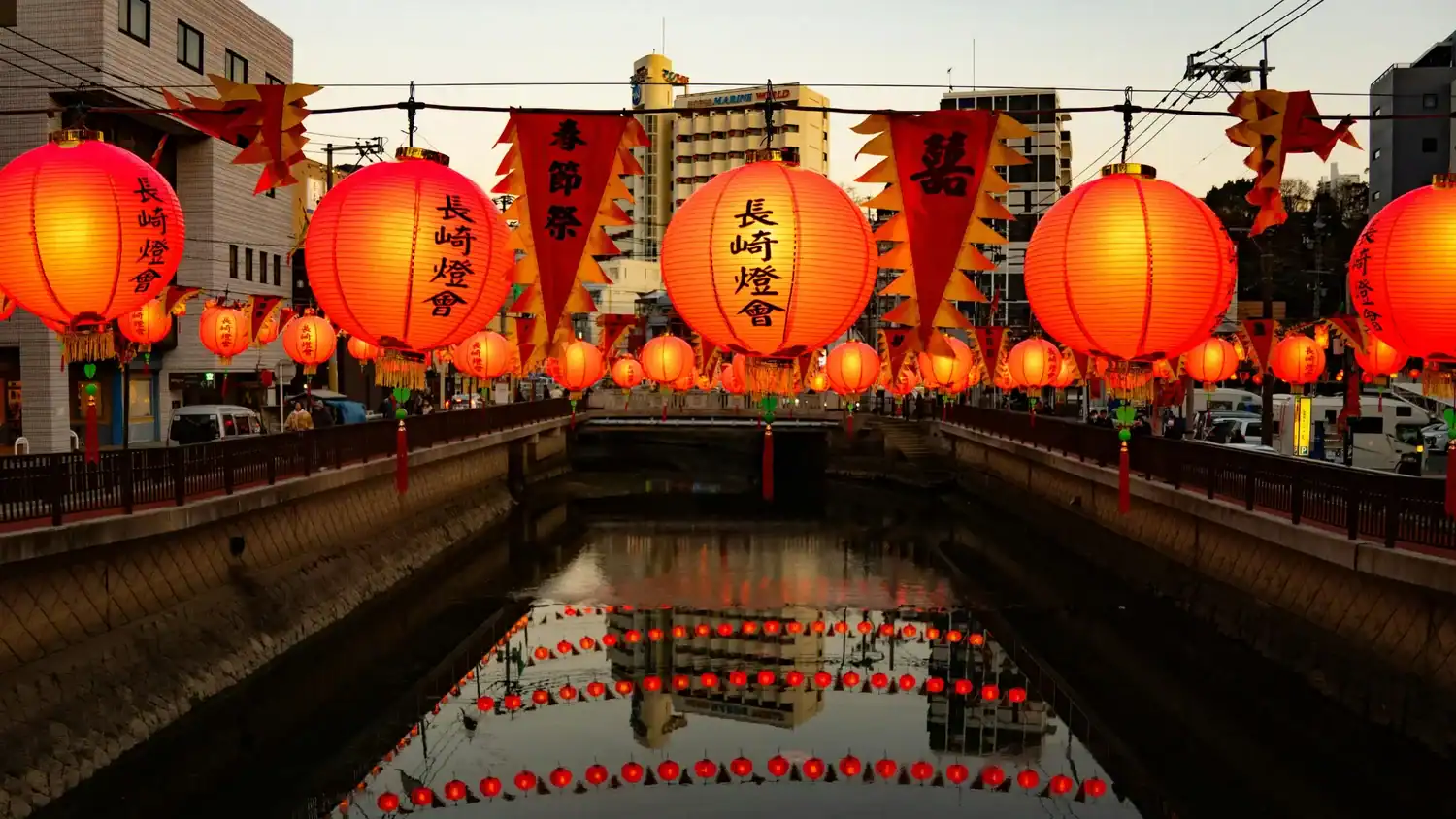 Traditional festivals in Japan shown through lanterns lining a canal during the Nagasaki Lantern Festival at dusk.