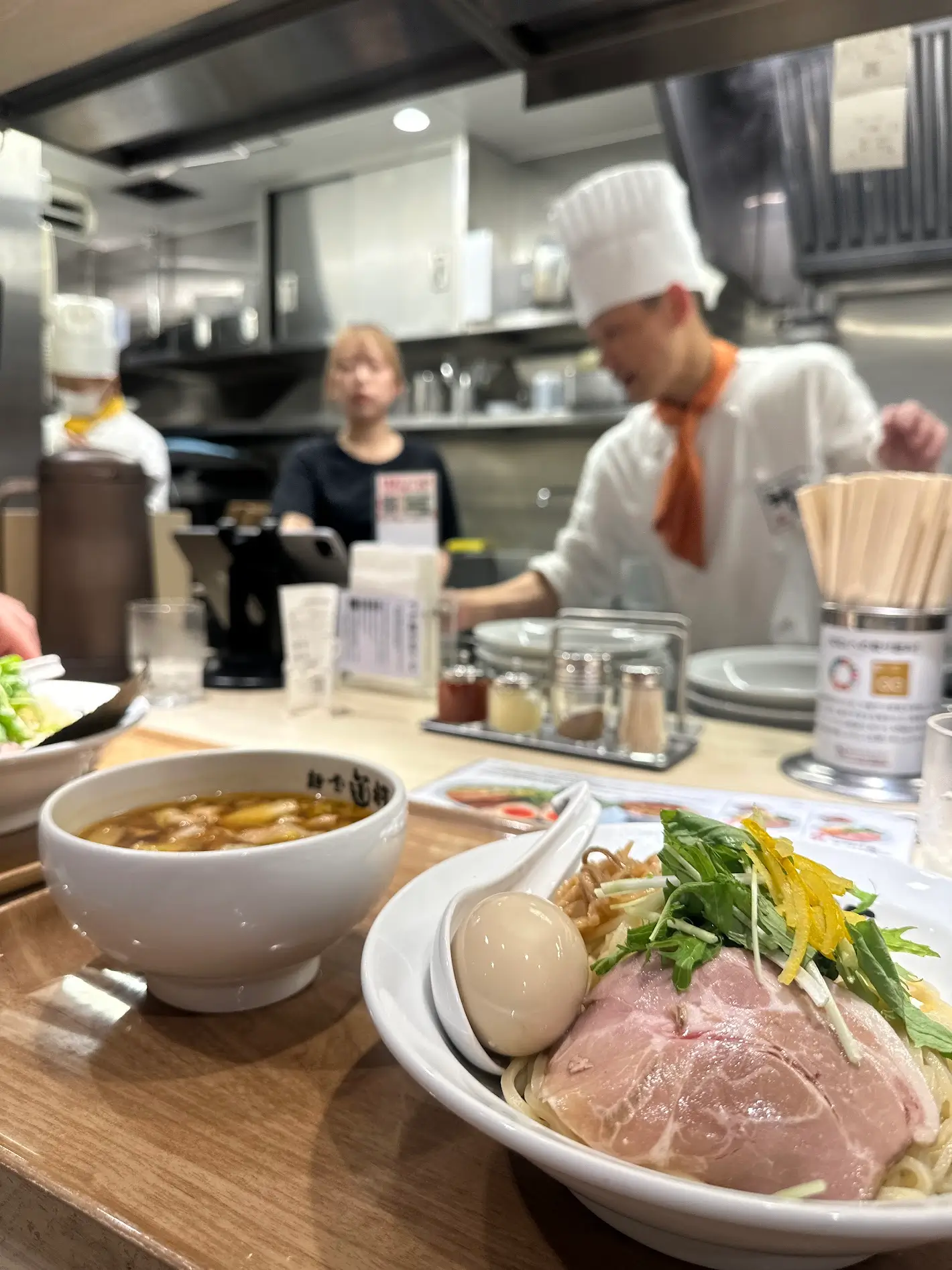 Ramen served at a counter-style Japanese restaurant with a chef preparing dishes, showcasing restaurant etiquette in Japan at counter seating. Restaurant Etiquette in Japan