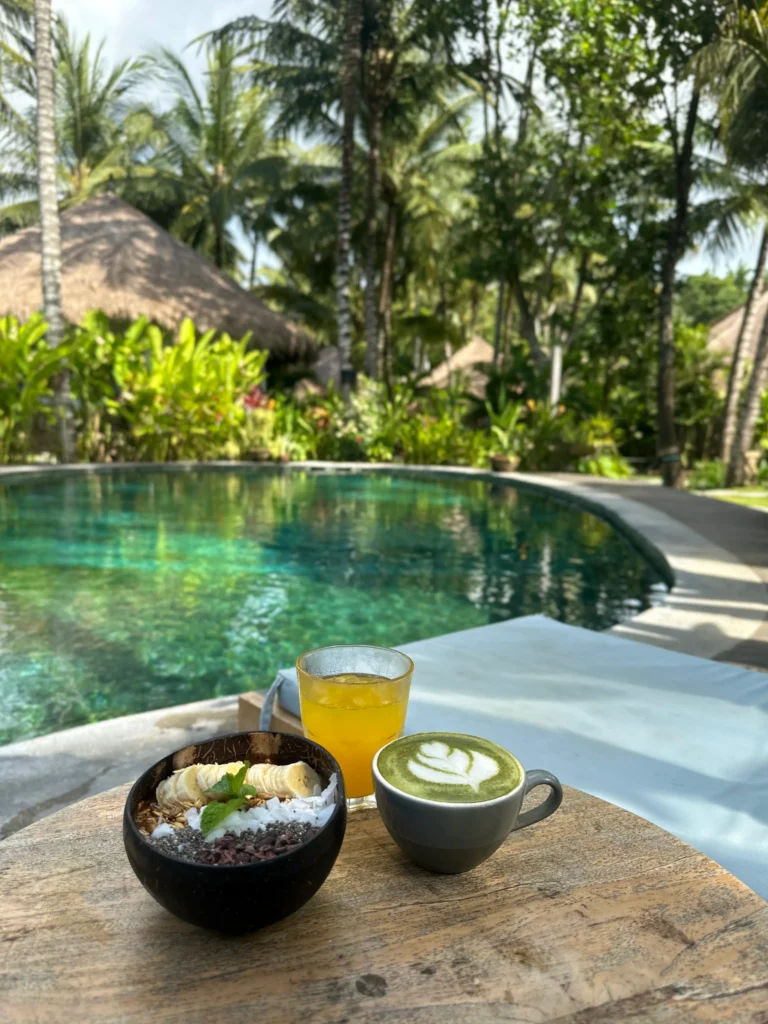 Breakfast by the pool at an eco-resort in Kuta Lombok, featuring banana porridge and matcha, one of the most relaxing things to do in Kuta Lombok