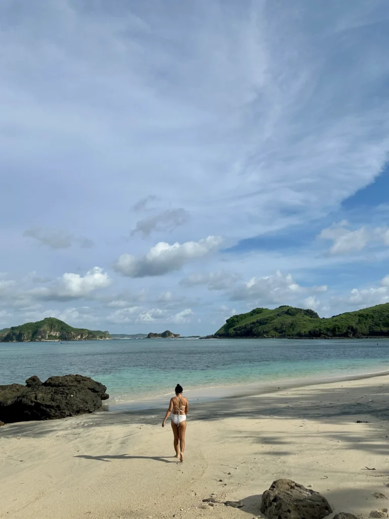 Woman walking along soft white sand at Tanjung Aan Beach, one of the most relaxing things to do in Kuta Lombok