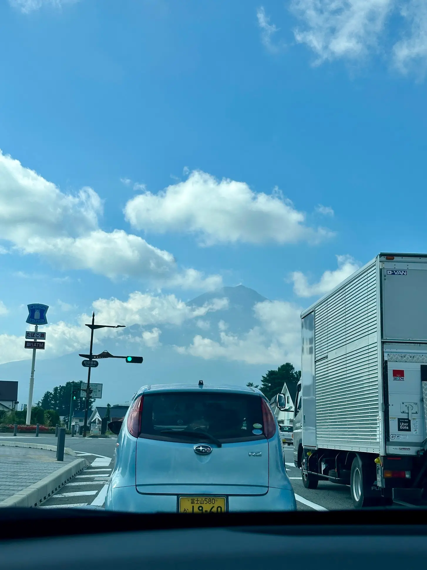 How to Rent a Car in Japan while driving on local roads, showing left-hand traffic, compact cars, and clear road signs on a sunny day.