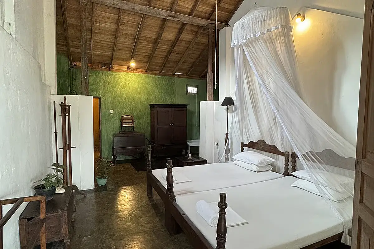 The interior of the retreat, featuring a bed with a canopy, green wallpaper, wooden floors and ceiling, and antique-looking cabinets and drawers.