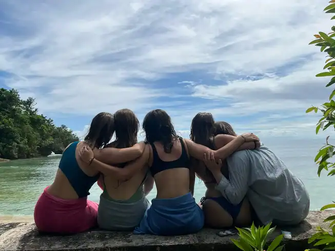 A group of girls huddling together and facing the beach.