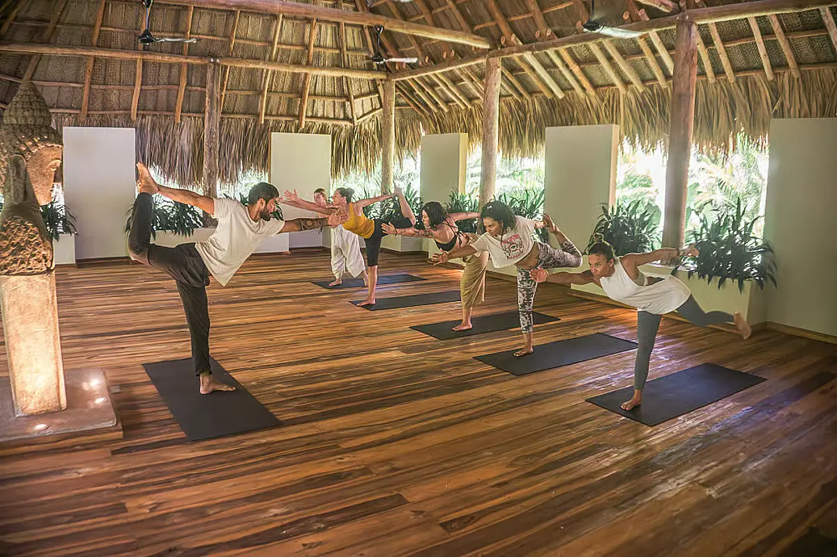 People hold their legs in a scorpion position in Senda Loto, one of the best yoga retreats in Colombia.