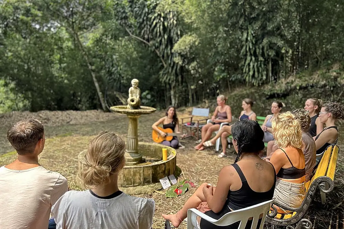 A group gathers around a Buddha statue while one person is holding a guitar, presumably serenading the others. 