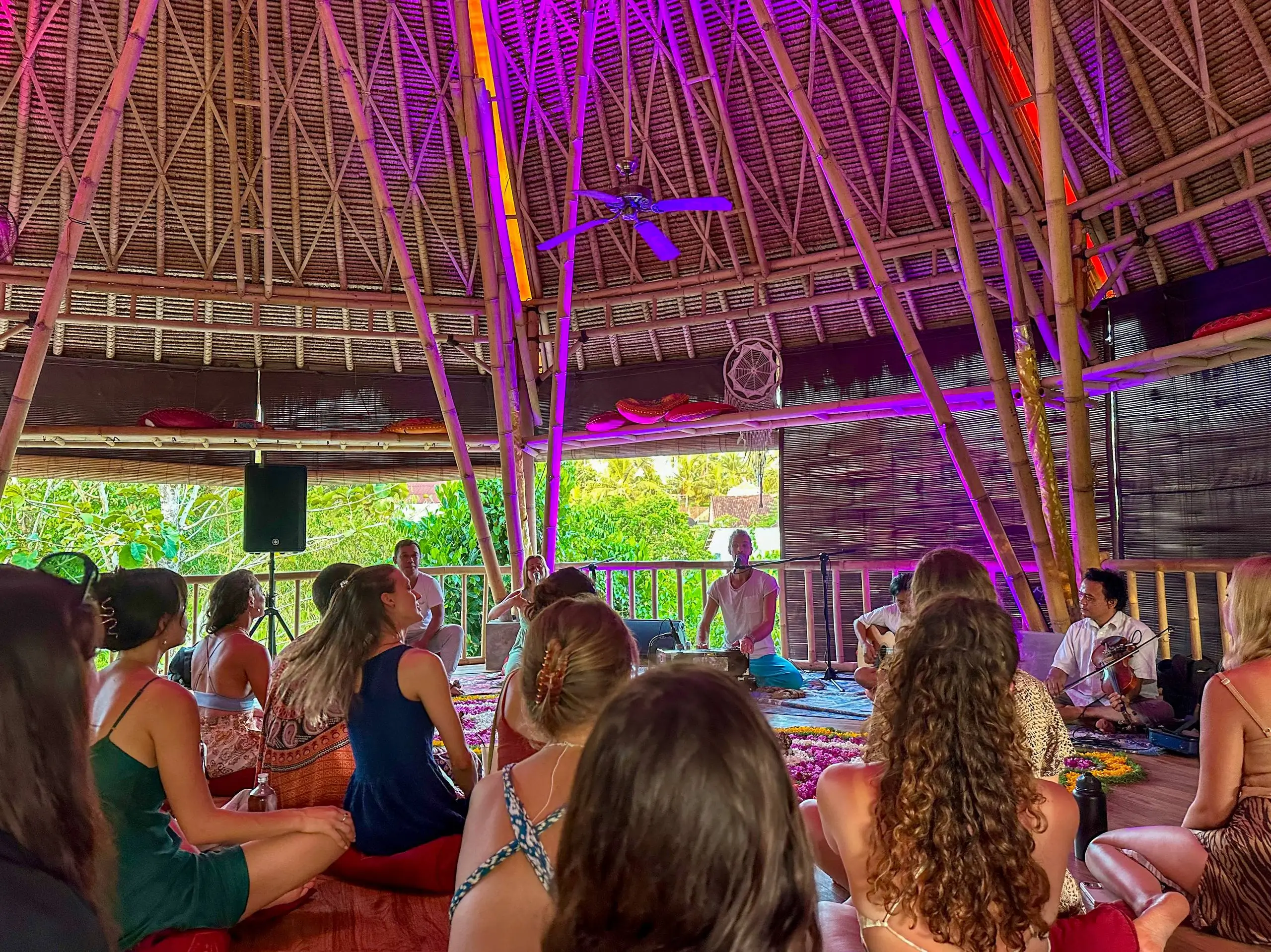 Group of people sitting in a bamboo pavilion during a kirtan session, representing wellness-focused things to do in Ubud