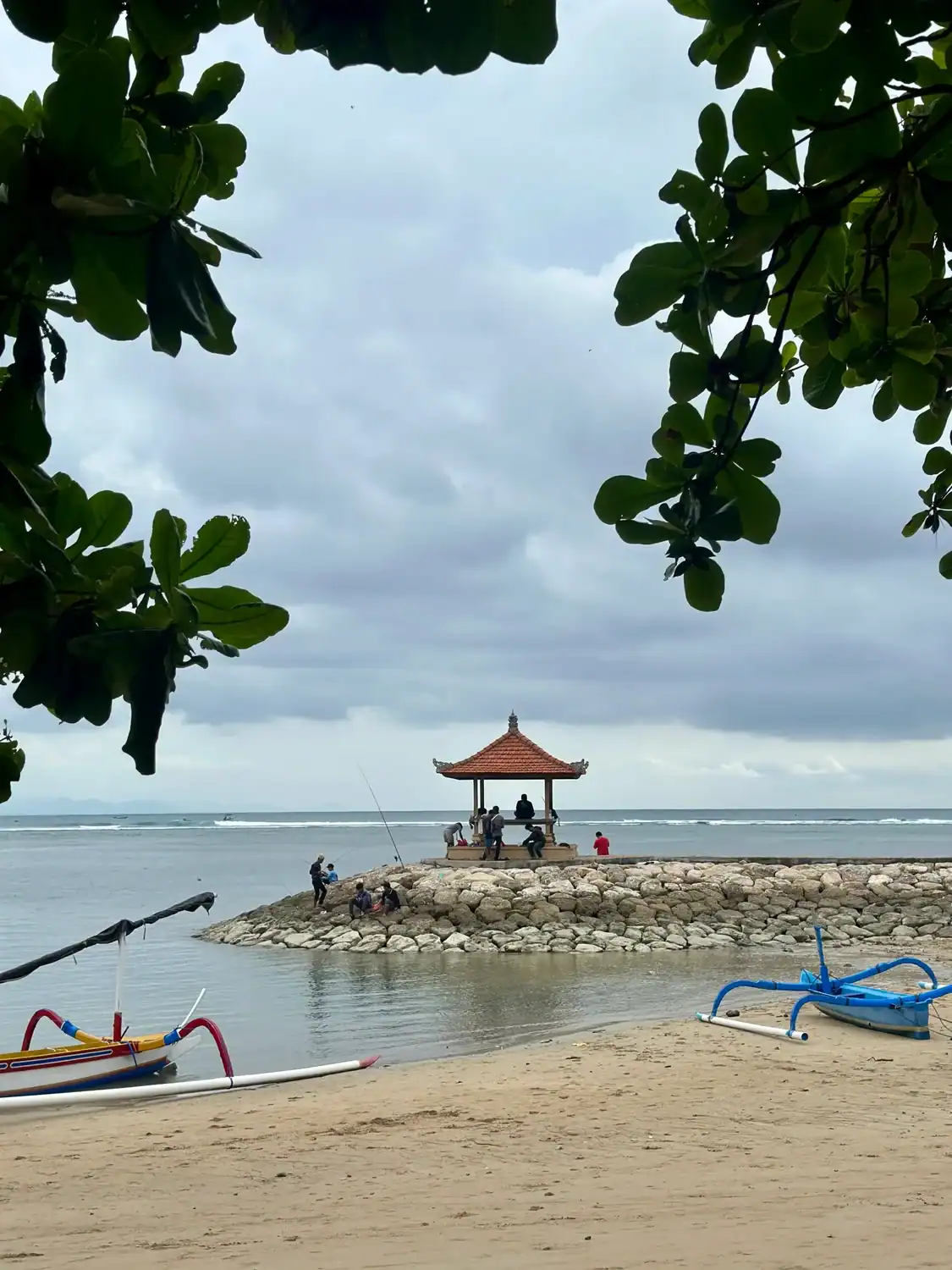 Sanur Beach in Bali with a small seaside pavilion and traditional boats