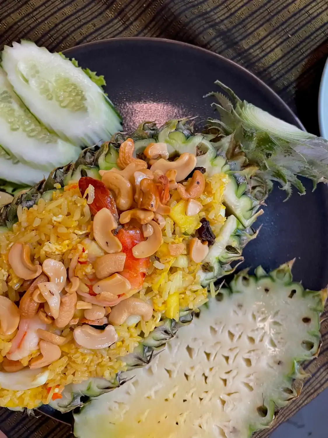 Pineapple fried rice served inside a hollowed pineapple and topped with roasted cashews, shrimp, and vegetables.