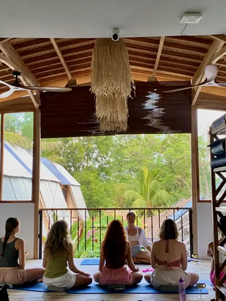 Volunteer in Thailand as a yoga instructor, leading a group meditation and yoga session in a peaceful hostel surrounded by nature.