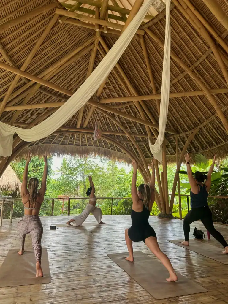 Students in Warrior pose inside the bamboo shala at SKY Yoga and Meditation during yoga teacher training in Bali