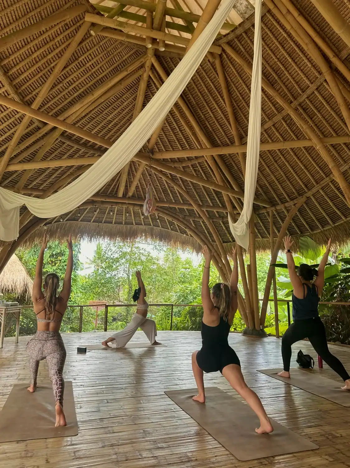 Students in Warrior pose inside the bamboo shala at SKY Yoga and Meditation during yoga teacher training in Bali
