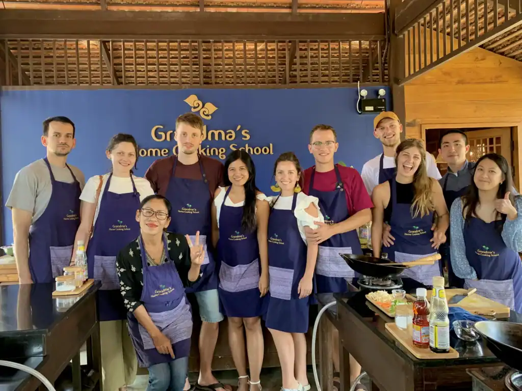 Participants posing together in aprons after completing a Chiang Mai cooking class at Grandma's Home Cooking School in Chiang Mai, Thailand.