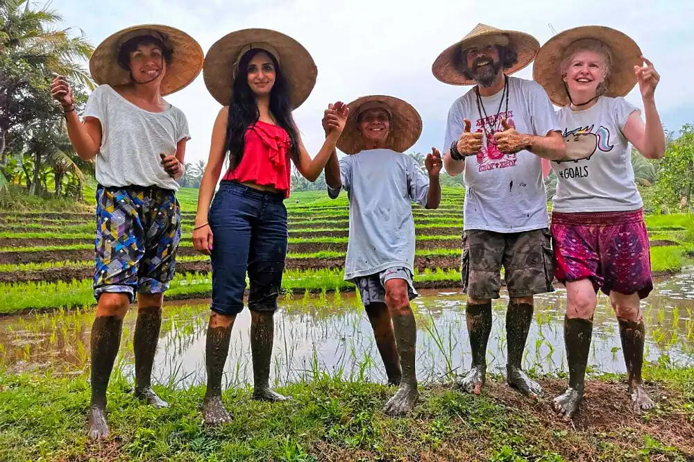 Guests in rice farmer hats in a Bali rice field, one of the experiences at wellness retreats in Bali