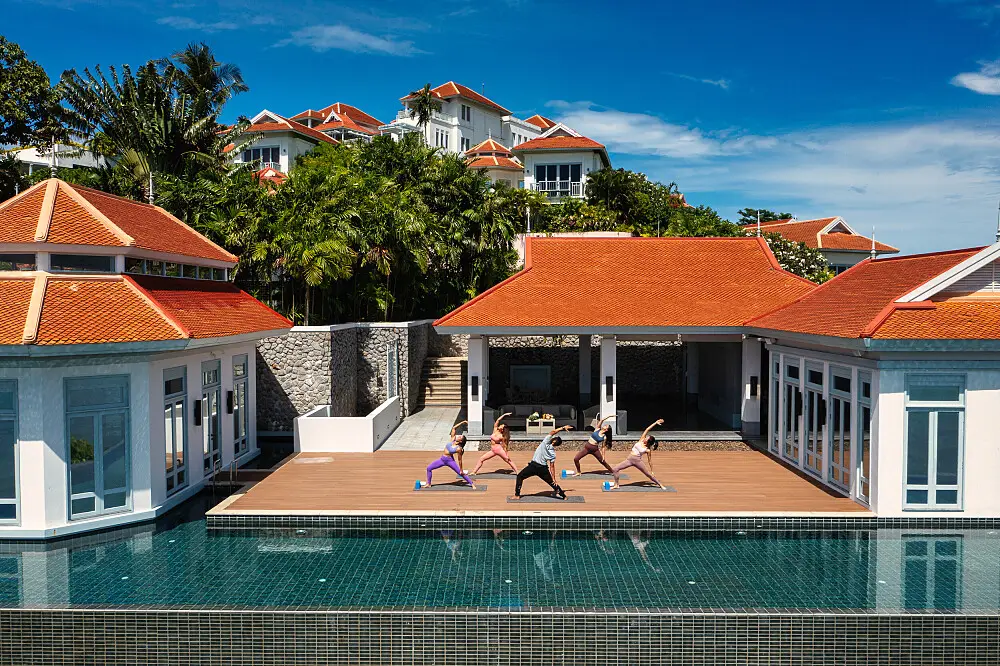 A small group practices yoga on a poolside deck at Amatara Welleisure Resort in Phuket