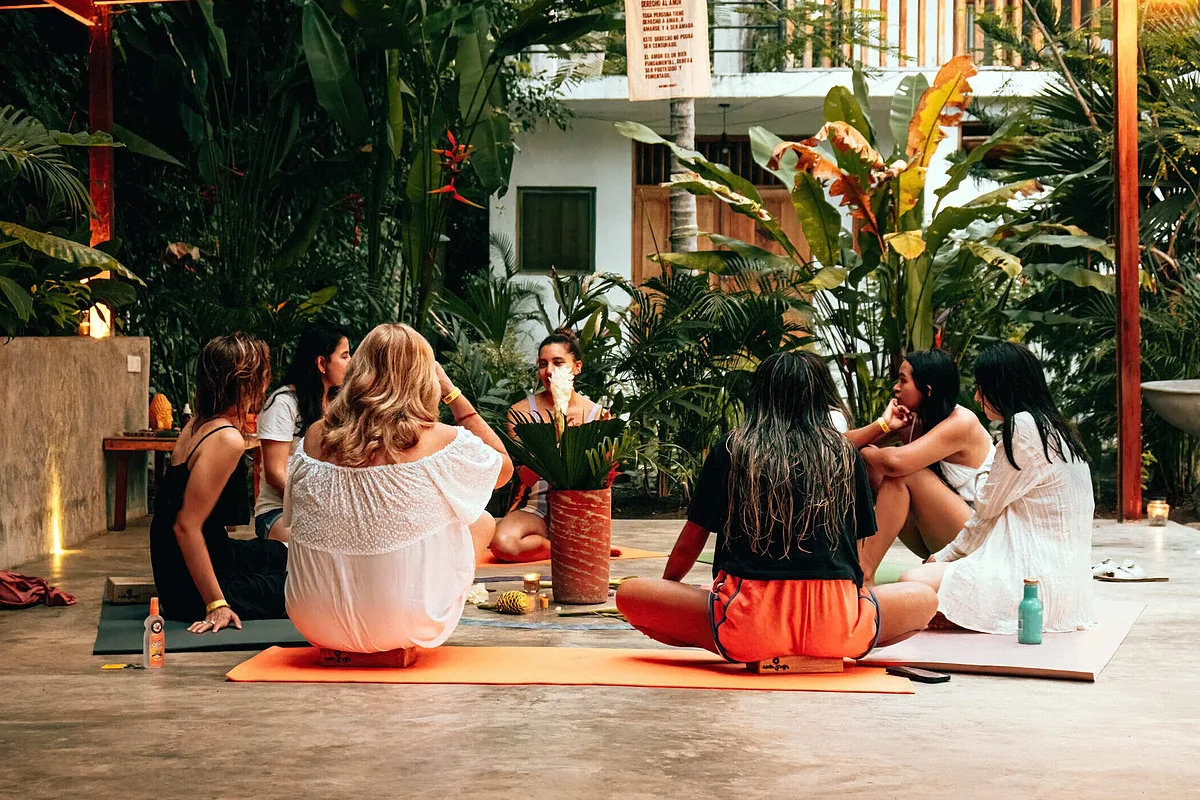 Women sitting together on yoga mats in a tropical garden at a yoga retreat in Palomino, Colombia